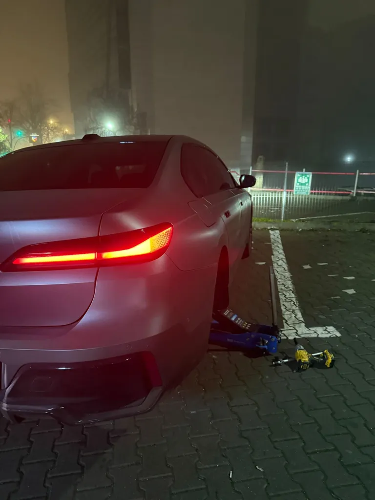 Autoturism alb la o intervenție de noapte, cu scule de vulcanizare lângă roată